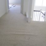 Loose and buckled off white berber carpet on upstairs landing before stretching